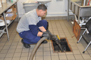 Russell Reid worker and equipment working on a commercial kitchen grease trap