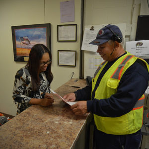 a truck driver inside the office signing paperwork