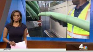 Woman on news with a russel reid truck in the background and a man taking out a green tube